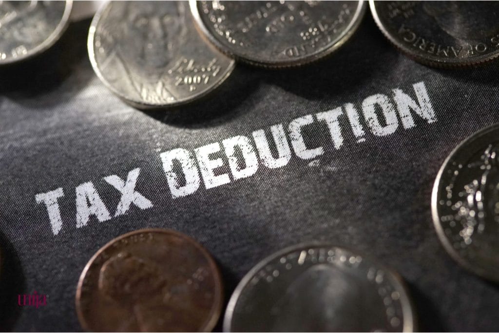 Tekst „tax deduction“ odštampan belim slovima na tamnoj površini, oko kojeg su razbacane kovanice, što simbolizuje pravo na odbitak prethodnog poreza.