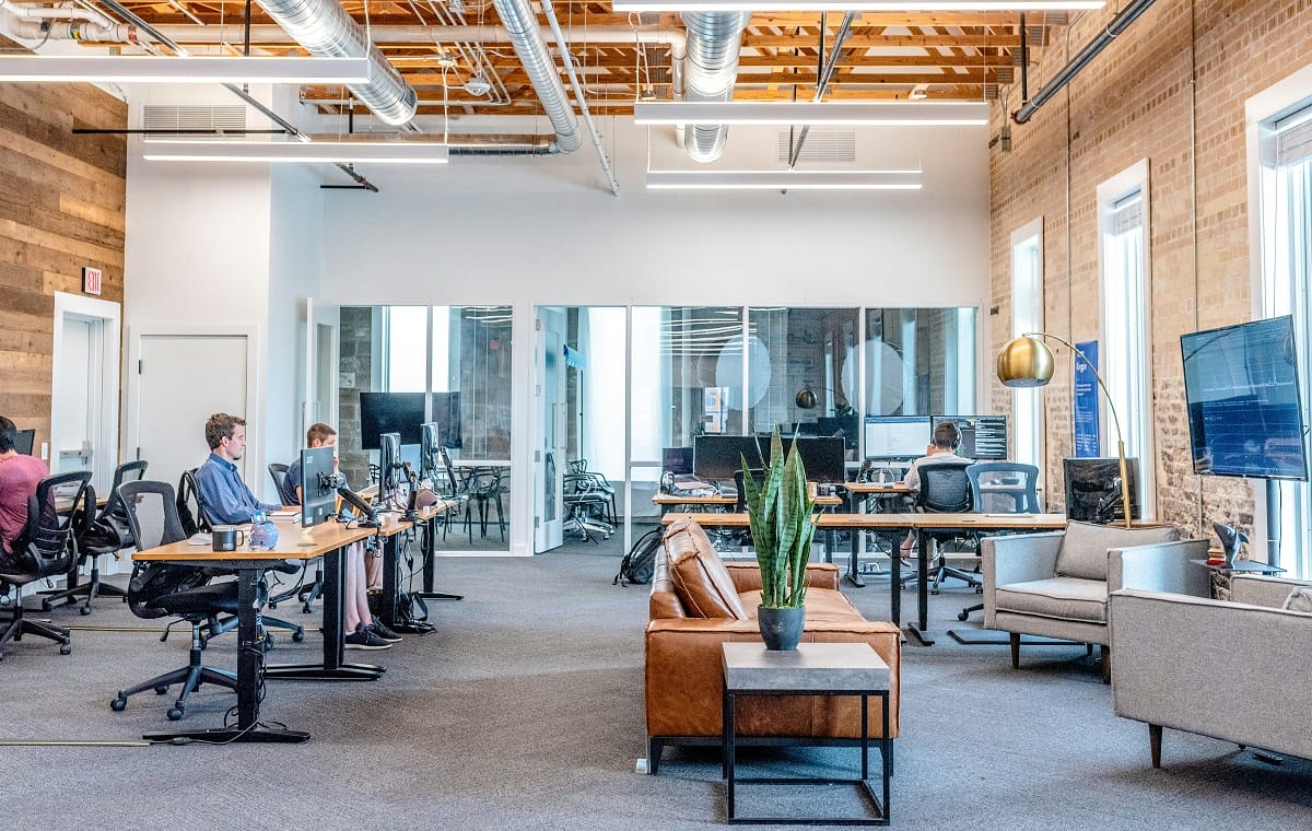 an office space with desks, computer and a couch for a medium company size