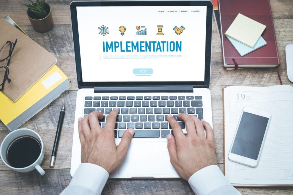 Osoba koristi laptop sa prikazom ESG implementacije, okružena planerom, šoljom kafe i radnim priborom - vizuelizacija procesa implementacije ESG strategije.