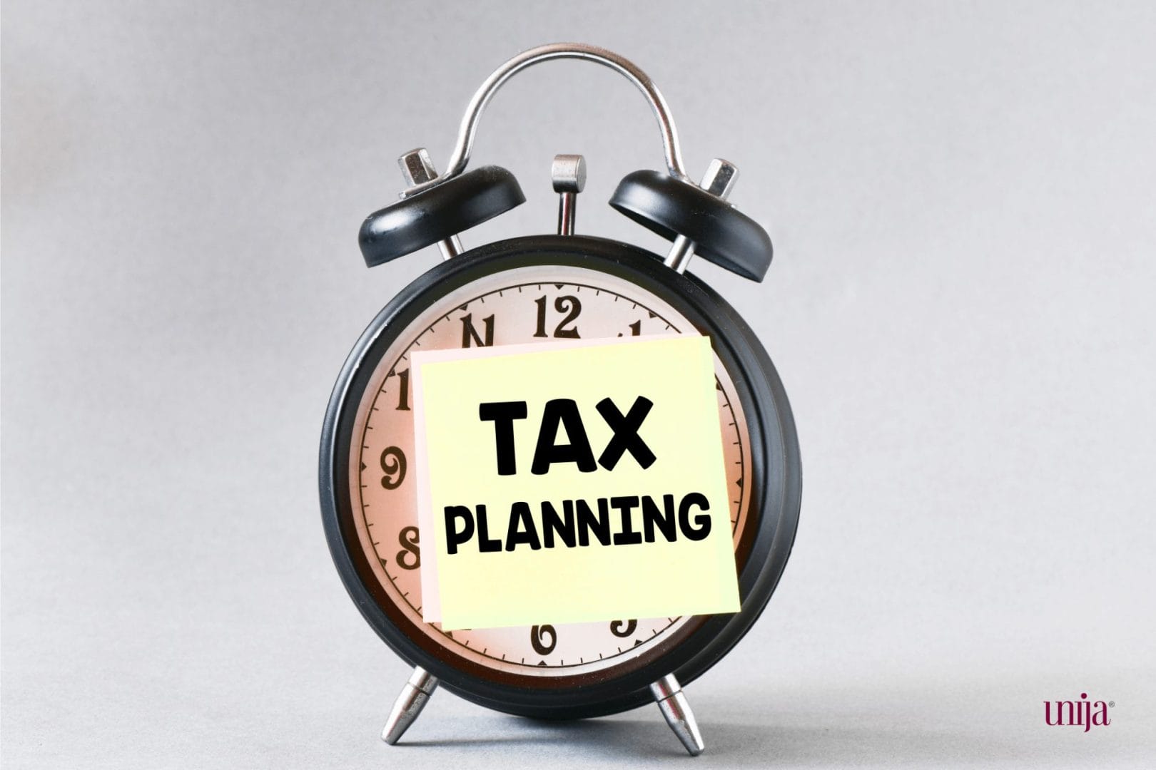 Analogni budilnik sa nalepnicom na kojoj piše tax planning, što simbolizuje poreski kalendar za januar 2025. godine.