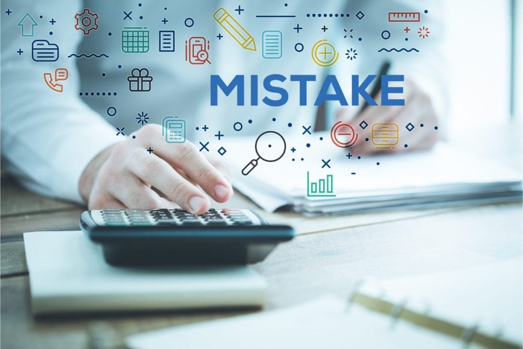 Ruka s kalkulatorom i riječ "MISTAKE" – simbol najčešćih pogrešaka u ESG izvještavanju.