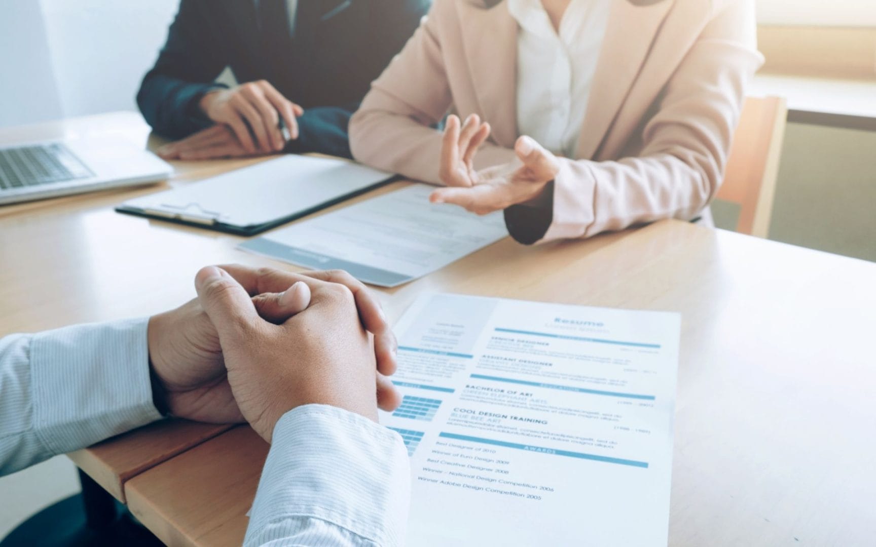 Dva poslovneža v pogovoru med razgovorom za delo, s CV-ji in dokumenti na mizi, spodbujanje zaposlovanja.