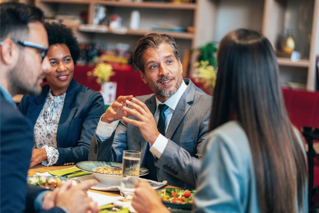Poslovni ljudi na ručku tokom neformalnog sastanka, što ilustrira situaciju relevantnu za porezni tretman troškova reprezentacije.